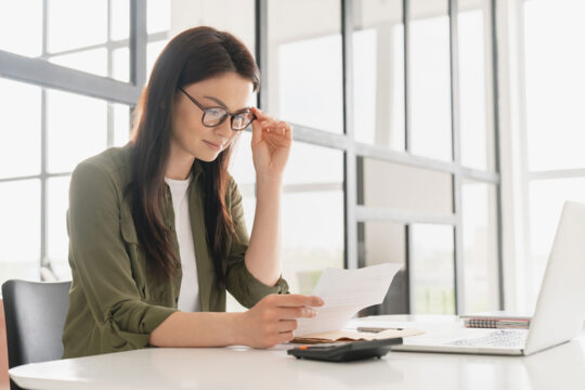 Une femme à lunettes assise dans un bureau et lisant un document