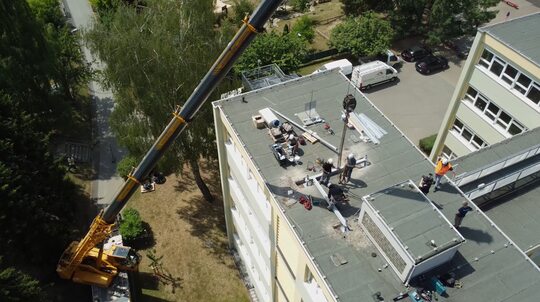 Une grue en train de déposer un colis sur un toit