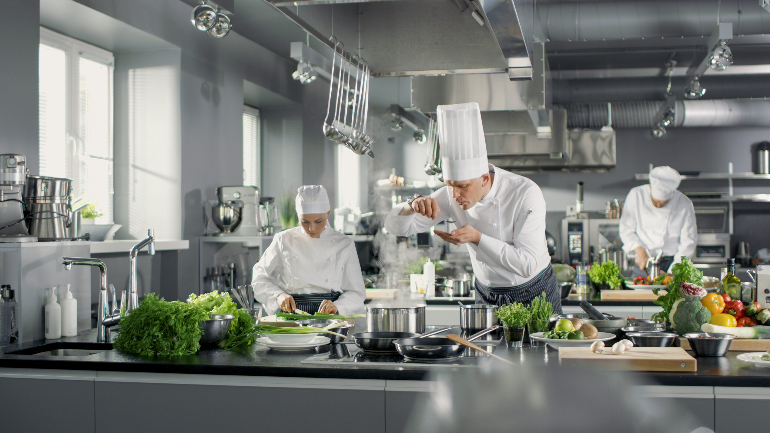 Mehrere Köche kochen in einer Großküche